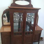 LOTE 040 - 01 CRISTALEIRA ANTIGA IMBUIA COM DETALHES ENTALHADOS NAS PORTAS, ESPELHOS LATERAIS, COM PORTA ENVIDRAÇADA EM CRISTAL BISOTADO. (NO ESTADO DE CONSERVAÇÃO QUE SE ENCONTRA) 