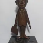 LOTE 008 - MINI ESCULTURA DE BRONZE NA BASE DE   MÁRMORE, MR. BEAN.  19CM (NO ESTADO)