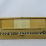 LOTE 078 - COLEÇÃO COM 20  MINIATURAS DE CAVALOS DE CORRIDA ANTIGOS DÉCADA DE 80 COM  JÓQUEIS EM CHUMBO, POLICROMADA, NO ESTOJO DE MADEIRA COM DIVISÓRIAS OBS DUAS MINIATURAS FALTANDO UMA PERNA (NO ESTADO)
