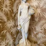 LOTE 093 - BELA ESCULTURA FEMININA EM PÓ DE MÁRMORE, AVALIADA EM 5 MIL REAIS COM BASE RICOS DETALHES. 1,52M TOTAL.  ESCULTURA: 76CM , BASE: 76CM (NO ESTADO)