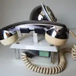 LOTE 084 - RARO TELEFONE ANOS 70. EM PLÁSTICO CROMADO E MECANISMO EM CAIXA DE ACRÍLICO MEDIDAS 24 CM COMP X 14,5 CM LARG X 19 CM ALT (NO ESTADO)