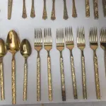 LOTE 117 - FAQUEIRO DOURADO PEÇAS: 6 TALHARES DE SERVIÇO, 12 COLHERES DE CHÁ, 5 COLHERES DE SOBREMESA, 2 GARFOS DE SOBREMESA, 9 GARFOS DE MESA, 5 COLHERES DE SOPA E 5 FACAS DE MESA.  44 PEÇAS (NO ESTADO)