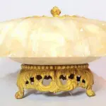 LOTE 176 - RARO TERNO IMPORTADO ITÁLIA, SÉC XIX, EM ALABASTRO, PARTES  EM BRONZE DOURADO, 1 CENTRO DE MESA-FLOREIRA,  GRANDE FLOR  UM PAR DE CASTIÇAIS PRA DUAS VELAS REPRESENTANDO ARPAS. MED 17X30 CM (CENTRO DE MESA) E 35X20 CM( CASTIÇAIS). (NO ESTADO)