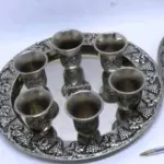 LOTE 145 - LINDA BANDEJA   COM 6 COPOS - EM METAL PRESSURIZADA A PRATA COM DETALHES DE CACHOS DE UVAS EM ALTO RELEVO MEDEM 24CM. (NO ESTADO)