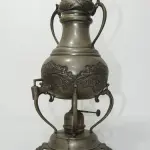 LOTE 156 - ANTIGO SAMOVAR EM METAL 52 DE ALTURA PESA  3,105KG (NO ESTADO)
