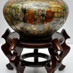 LOTE 284 - RARÍSSIMO VASO IMPORTADO EM FAIANCA CHINESA. ACOMPANHA BASE EM MADEIRA CLARA. ALT DO VASO: 17 CM. ALT DA BASE: 15,5 CM. MARCA NO FUNDO. (NO ESTADO)