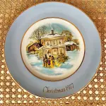 01 LINDO PRATO DE NATAL DA SÉRIE AVON CHRISTMAS PLATE DE 1977, "CAROLLERS IN THE SNOW" - QUINTA EDIÇÃO DA SÉRIE. COM 22 CM DE DIÂMETRO E RETRATA UM GRUPO DE CANTORES DE NATAL EM FRENTE A UMA CASA DE DOIS ANDARES NO CENTRO. O VERSO MARCADO: SÉRIE DE PRATOS DE NATAL QUINTA EDIÇÃO "CANTORES DE NATAL NA NEVE" COM DOIS ANÉIS DE OURO 22K E O NATAL DE 1979 TAMBÉM EM OURO 22K.  FEITO EXCLUSIVAMENTE PARA A AVON CTS INC., 1977 POR ENOCH WEDGWOOD (TUNSTALL) LTD., INGLATERRA PEÇA COMPRADA EM GARAGEM DE ANTIGUIDADES NOS EUA. SUPORTE PARA PRATO NÃO INCLUÍDO NESTA VENDA. (NO ESTADO) ATENÇÃO! FAZER A VISITAÇÃO ANTES DE ARREMATAR, NÃO SABEMOS SE FUNCIONA, LEILÃO NÃO TEM GARANTIA E NEM DEVOLUÇÃO, SUJEITO A POSSÍVEIS AVARIAS VISÍVEIS/OCULTAS E/OU AUSÊNCIA DE COMPONENTES.