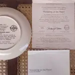 01 PRATO DE NORMAN ROCKWELL EDIÇÃO LIMITADA "A 100 DIAS DE QUEIMA DE ESTOQUE" DA SÉRIE MULHERES REDESCOBERTAS, "PONDERING ON THE PORCH"3º PRATO DA SÉRIE MULHERES REDESCOBERTAS,21,5 CM DE DIÂMETRO, BRADEX Nº 84-R70-4.3 1981 EDWIN M. KNOWLES CHINA COMPANY UM GENUÍNO CLÁSSICO ROCKWELL. FINA EDWIN M KNOWLES. COM CERTIFICADO DE AUTENTICIDADE, FEITO NOS ESTADOS UNIDOS. PERFEITO PARA FÃS DA ICÔNICA OBRA DE ROCKWELL, ESTE PRATO DE COLECIONADOR É UM ITEM ESSENCIAL PARA QUALQUER COLEÇÃO. ADICIONE ESTA PEÇA DESLUMBRANTE À SUA COLEÇÃO HOJE MESMO E ADMIRE OS DETALHES COMPLEXOS E AS BELAS CORES QUE FAZEM DESTE PRATO UMA OBRA DE ARTE. COM CERTIFICADO DE AUTENTICIDADE. ITEM COMPRADO E GARAGENS DE ANTIGUIDADES NOS EUA.SUPORTE PARA PRATO NÃO INCLUÍDO NESTA VENDA. (NO ESTADO) ATENÇÃO! FAZER A VISITAÇÃO ANTES DE ARREMATAR, NÃO SABEMOS SE FUNCIONA, LEILÃO NÃO TEM GARANTIA E NEM DEVOLUÇÃO, SUJEITO A POSSÍVEIS AVARIAS VISÍVEIS/OCULTAS E/OU AUSÊNCIA DE COMPONENTES.