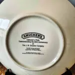 01 LINDO PRATO DE NATAL DA SMUCKER'S COM 21 ,5 FAZIA PARTE DE UMA SÉRIE PARA COLECIONADORES E ERA INCLUÍDO EM UM PACOTE ANUAL DE PRESENTES DE NATAL CONTENDO UMA VARIEDADE DE GELEIAS E COMPOTAS DA SMUCKER'S. DAVID PROJETOU SEU PRIMEIRO PRATO PARA A SMUCKER'S EM 1972, COM OS PRIMEIROS DEZ PRATOS APRESENTANDO CENAS NATALINAS DE TODOS OS LUGARES, INCLUINDO A WILLIAMSBURG COLONIAL, A FILADÉLFIA HISTÓRICA, O VALE DO MISSISSIPPI E ATÉ MESMO A SUÍÇA. NO ENTANTO, A PARTIR DE 1982, A ARTE DE DAVID PARA A SÉRIE DE PRATOS RETRATAVA PRÉDIOS HISTÓRICOS E CENÁRIOS RURAIS DURANTE A TEMPORADA DE FÉRIAS EM TODO O ESTADO DE OHIO, SEDE DA SMUCKER COMPANY. AO LONGO DOS ANOS, MUITOS PRATOS DE NATAL CAPTURARAM A AUTENTICIDADE E O ESPÍRITO NATALINO DA COMUNIDADE DA SMUCKER'S, APRESENTANDO LOCAIS DENTRO E AO REDOR DA CIDADE DE ORRVILLE, SEDE DA EMPRESA, E OUTRAS PARTES DO CONDADO DE WAYNE. APÓS CINQUENTA ANOS, DAVID COMPLETOU ESTA SÉRIE COM UM PRATO FINAL PRODUZIDO EM 2021.  ITEM COMPRADO EM GARAGENS DE ANTIGUIDADES NOS EUA. SUPORTE PARA PRATO NÃO INCLUÍDO NESTA VENDA. (NO ESTADO) ATENÇÃO! FAZER A VISITAÇÃO ANTES DE ARREMATAR, NÃO SABEMOS SE FUNCIONA, LEILÃO NÃO TEM GARANTIA E NEM DEVOLUÇÃO, SUJEITO A POSSÍVEIS AVARIAS VISÍVEIS/OCULTAS E/OU AUSÊNCIA DE COMPONENTES.