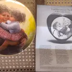 01 LINDO PRATO DE COLECIONADOR DE SUE ETEM "LOVE IN YOUR HEART", ASSINADO À MÃO O PRATO TEM 21 CM É O Nº 5421 DE UMA EDIÇÃO LIMITADA DE 40.000 EXEMPLARES NO TOTAL DA AMERICAN LEGACY LTD. 1984 E RETRATA DUAS CRIANÇAS SE ABRAÇANDO. SUE ETEM É CONHECIDA POR SUAS BELAS REPRESENTAÇÕES DE CRIANÇAS EM CORES VIBRANTES E DIMENSÕES, E O PRATO É ASSINADO POR ELA NO VERSO, EM SUA CAIXA ORIGINAL. PEÇA COMPRADA EM GARAGEM DE ANTIGUIDADES NOS EUA. SUPORTE PARA PRATO NÃO INCLUÍDO NESTA VENDA. (NO ESTADO) ATENÇÃO! FAZER A VISITAÇÃO ANTES DE ARREMATAR, NÃO SABEMOS SE FUNCIONA, LEILÃO NÃO TEM GARANTIA E NEM DEVOLUÇÃO, SUJEITO A POSSÍVEIS AVARIAS VISÍVEIS/OCULTAS E/OU AUSÊNCIA DE COMPONENTES.