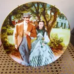 01  PRATO DE COLECIONADOR "E O VENTO LEVOU" DE 1989, "THE HOME TO TARA", É UMA ADIÇÃO DESLUMBRANTE À COLEÇÃO DE QUALQUER COLECIONADOR. APRESENTANDO A ICÔNICA MANSÃO DO ADORADO FILME, ESTE PRATO CAPTURA A GRANDIOSIDADE E A BELEZA DE "E O VENTO LEVOU". FABRICADO EM 1989, ESTE ITEM DE COLECIONADOR É ESSENCIAL PARA OS FÃS DO CLÁSSICO. COM DETALHES MINUCIOSOS E ACABAMENTO PRIMOROSO, ESTE PRATO É A MANEIRA PERFEITA DE COMEMORAR A HISTÓRIA ATEMPORAL DE SCARLETT O'HARA E RHETT BUTLER. QUINTA EDIÇÃO DA SÉRIE BODAS DE OURO DE 1989, OFICIALMENTE AUTORIZADA PELA METRO-GOLDWYN-MAYER PARA COMEMORAR O 50º ANIVERSÁRIO DO FILME IMORTAL "E O VENTO LEVOU".QUEIMADO EM PORCELANA FINA W. S. GEORGE COM DETALHES DOURADOS. EDIÇÃO LIMITADA A 150 DIAS DE QUEIMA.O PRATO MEDE 21,5 CM DE DIÂMETRO.PRATO DE NUMERO 4477K.COM TODA DOCMUENTAÇAO E CERTIFICADO DE AUTETICIDADE. PEÇA COMPRADA EM GARAGEM DE ANTIGUIDADES NOS EUA. SUPORTE PARA PRATO NÃO INCLUÍDO NESTA VENDA. (NO ESTADO) ATENÇÃO! FAZER A VISITAÇÃO ANTES DE ARREMATAR, NÃO SABEMOS SE FUNCIONA, LEILÃO NÃO TEM GARANTIA E NEM DEVOLUÇÃO, SUJEITO A POSSÍVEIS AVARIAS VISÍVEIS/OCULTAS E/OU AUSÊNCIA DE COMPONENTES.